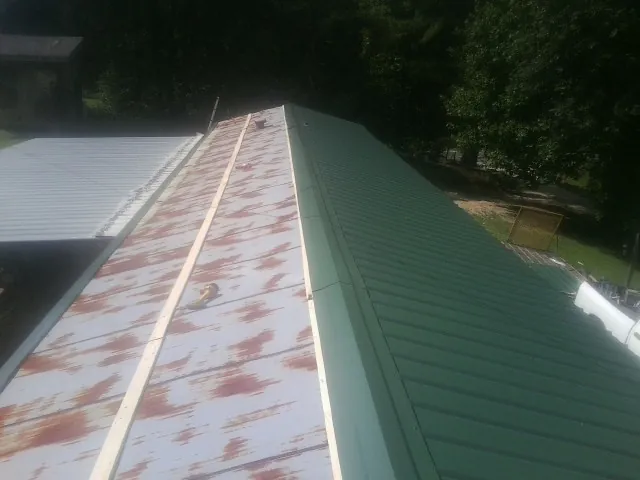 Old rusted panels beside newly installed green metal roofing — Wind Damage Roof Repair by Roofing Brothers in Lincoln Park