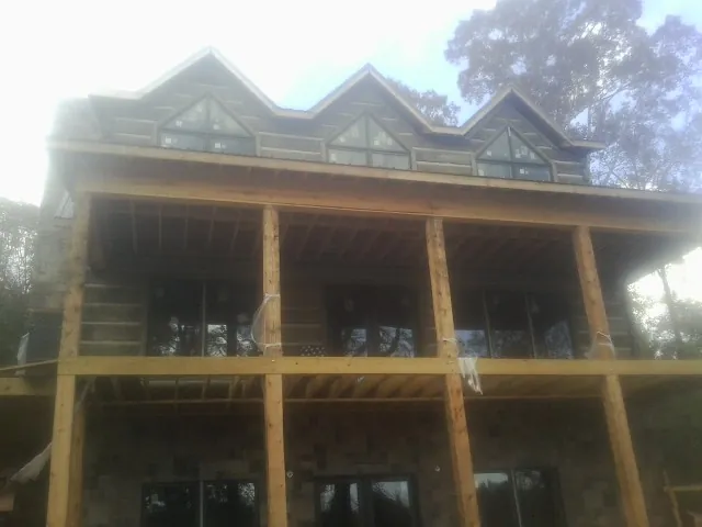 Dormers and porch framing on a large log home under construction — Roof Coating work by our crew in Lincoln Park
